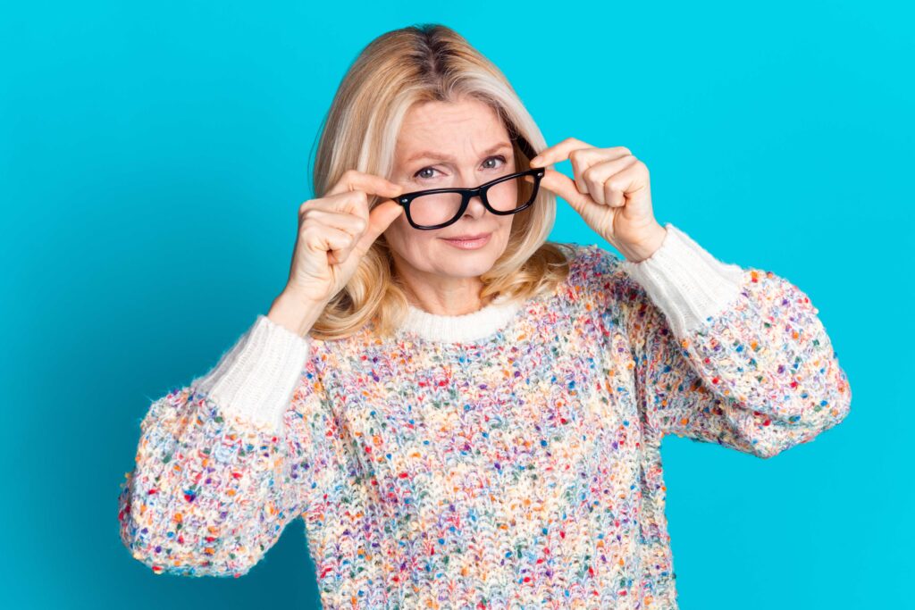 Una donna tocca i propri occhiali da vista mostrando un'espressione di attenzione rispetto alle novità sulle pensioni nel 2025