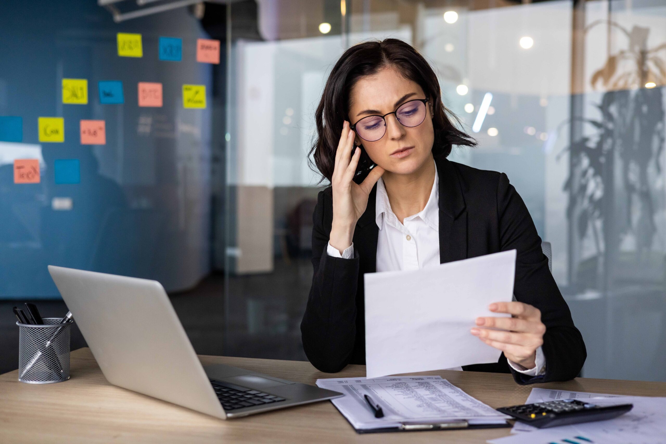 Donna in ufficio guarda con attenzione alcuni documenti che riguardano una domanda di pensione anticipata con opzione donna