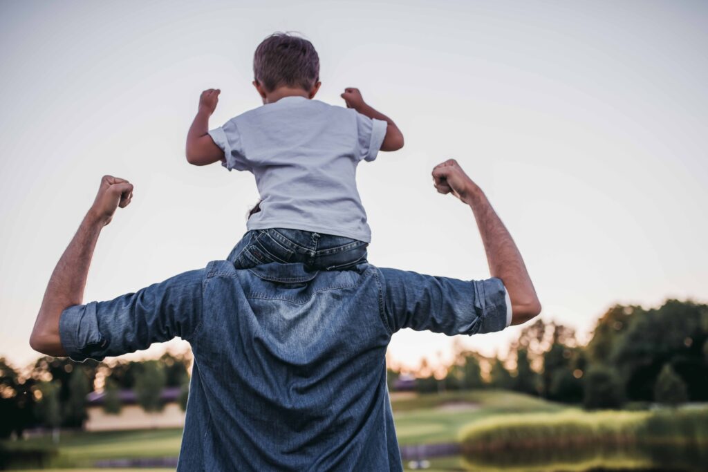 Papà e figlio di spalle mostrano felicità mentre trascorrono del tempo insieme in un parco durante il periodo di congedo riservato ai papà al lavoro