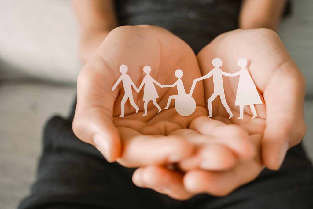 Mani con dei ritagli di carta a forma di persone varie, una famiglia. Simbolo di welfare, come nell'articolo di cui trattiamo: le differenze tra l'invalidità civile e l'assegno ordinario di invalidità