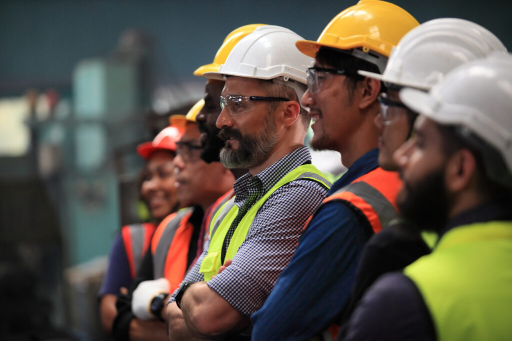Gruppo di lavoratori a braccia conserte sul posto di lavoro fermi nel rivendicare maggiori tutele sul tema degli infortuni sul lavoro e delle malattie professionali